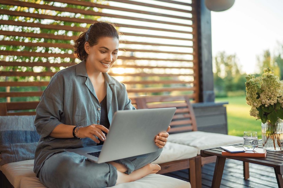 Junge Frau auf der Terrasse mit Laptop